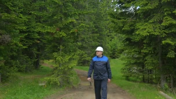 Працівник з планшетним ПК, що йде лісовою дорогою — стокове відео