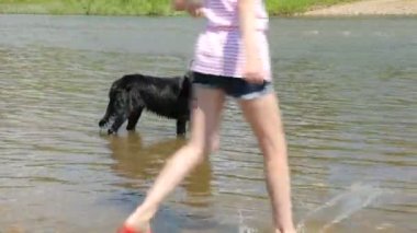 Nehirde köpeğiyle oynayan bir kız.