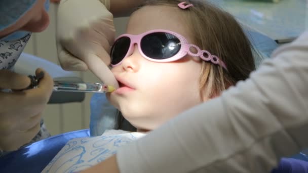 Little girl in dentist's chair having her tooth treated — Stock Video