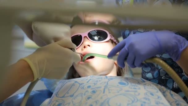 Mała dziewczynka na fotelu dentystycznym, która leczy zęby. — Wideo stockowe