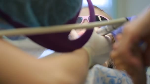 Klein meisje in de tandartsstoel die haar tand laat behandelen — Stockvideo