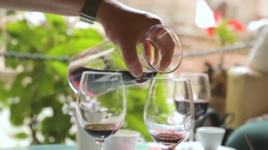 Caddedeki kafede şarap bardaklarına şarap dolduran adam.