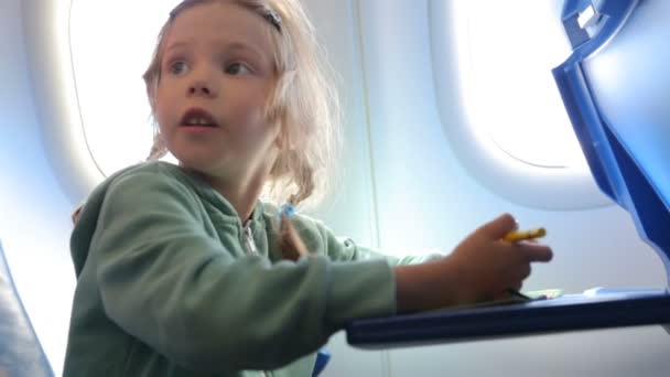 Ένα κοριτσάκι ζωγραφίζει στο αεροπλάνο. — Αρχείο Βίντεο