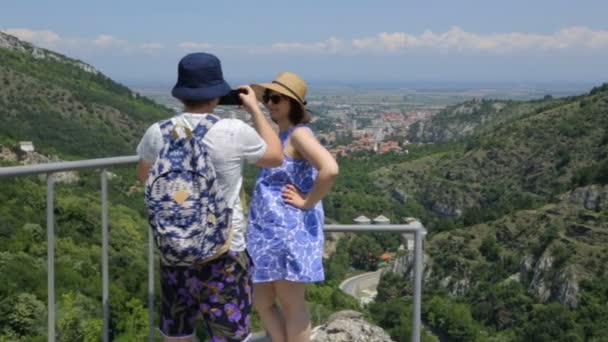 Joven tomando fotos de su esposa en la montaña — Vídeo de stock