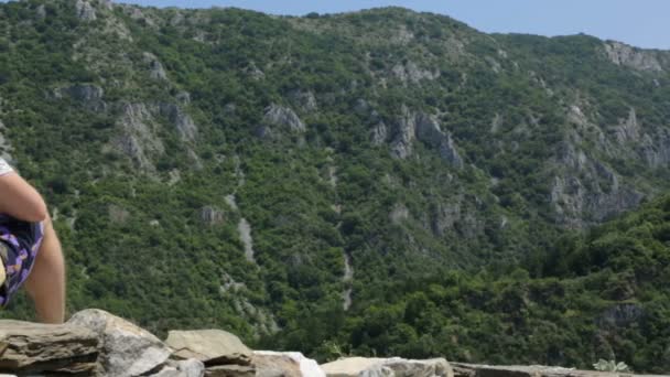 Turista en muro de piedra en las montañas — Vídeo de stock