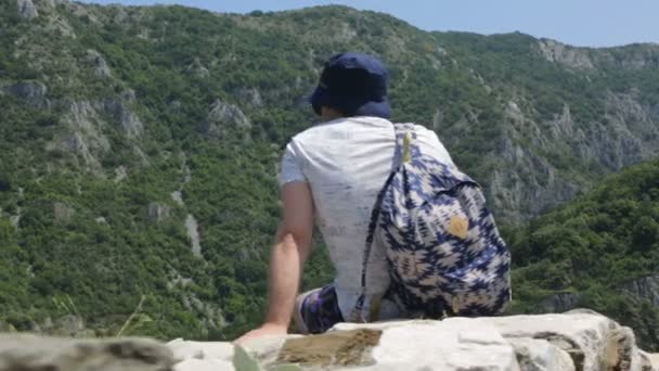 Turista en muro de piedra en las montañas — Vídeo de stock