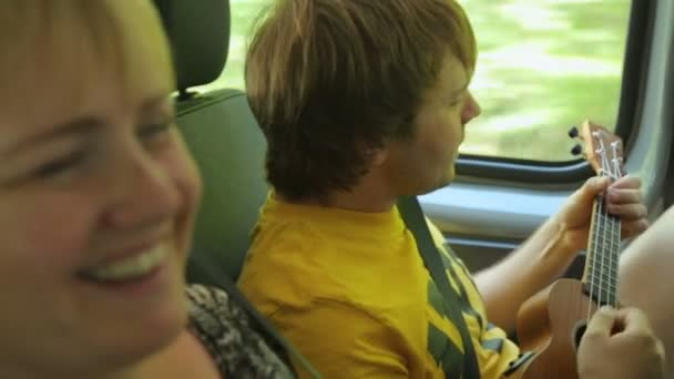 Jovem turista masculino jogar ukulele no carro — Vídeo de Stock