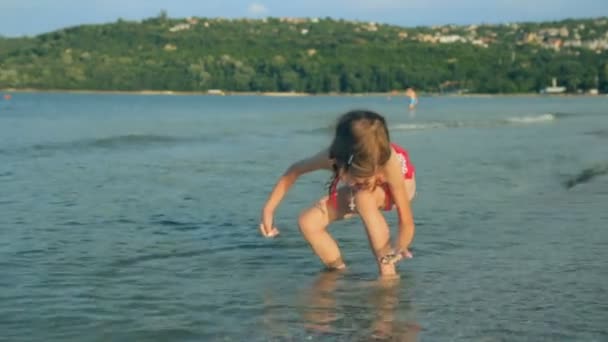 Mała dziewczynka na wybrzeżu w letni dzień — Wideo stockowe