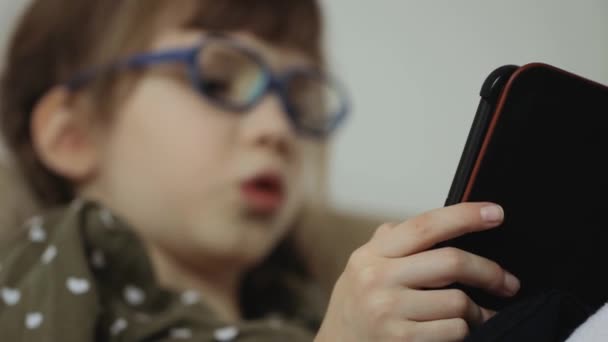 Niña leyendo libro electrónico en el sofá en casa — Vídeos de Stock