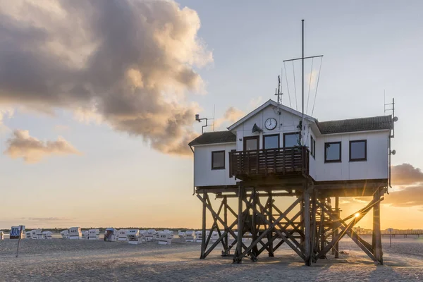 Dřevěný dům na kůlech na pláži při západu slunce — Stock fotografie