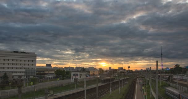 Time lapse cityscape com muitos trilhos ferroviários e movimento de trem elétrico de passageiros pendulares sobre eles. Movimento das nuvens com o pôr do sol ao fundo . — Vídeo de Stock