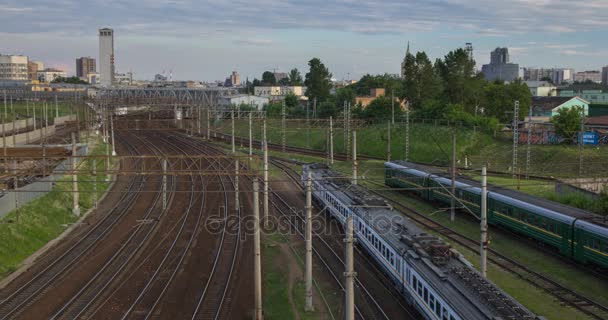 Міський пейзаж з багатьма залізничними коліями на передньому плані і переміщенням пасажирського поїзда — стокове відео