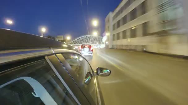 Conducir en la carretera nocturna de la ciudad en el cruce de carreteras. Un lapso de tiempo borroso. Vista desde el exterior de la cabina — Vídeo de stock