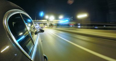 Araba gece şehir yolda yüksek hızda hareket ediyor.
