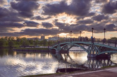 Gün batımında Tsaritsyno Parkı 'nda doğu kemerli köprü. Arka planda müzik fıskiyesi ve Tsaritsyno bölgesi. Moskova, Rusya.
