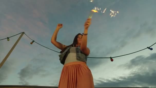 Woman jumping while holding firework candle — Stock Video