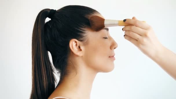 Main appliquant de la poudre sur le visage féminin — Video