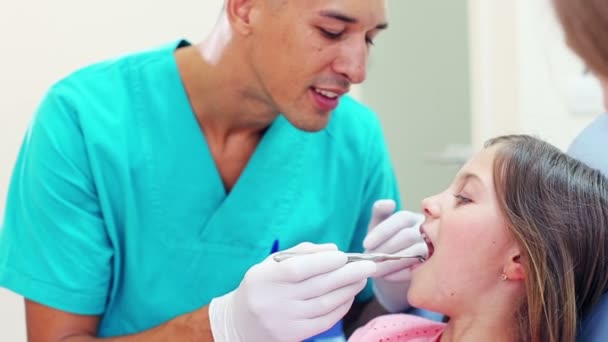 Cirujano examinando los dientes de niña — Vídeo de stock