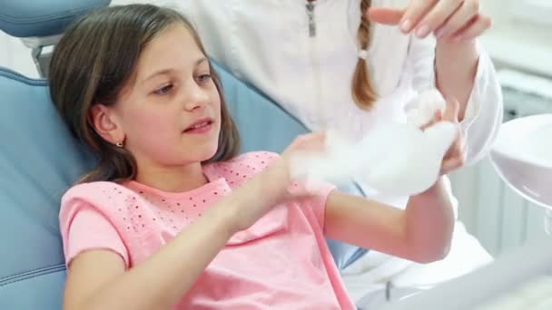 Девушка и стоматолог играют с резиновой перчаткой — стоковое видео
