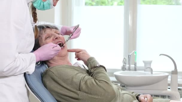 Женщина показывает зубной зуб дантисту — стоковое видео