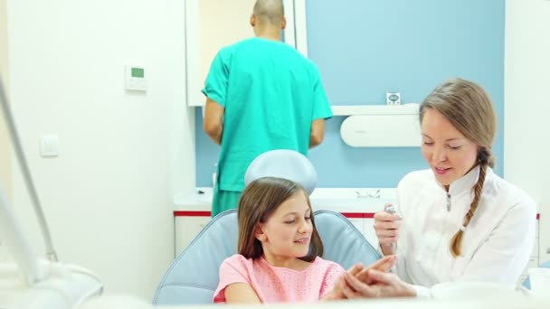 Стоматолог показывает инструменты пациенту — стоковое видео