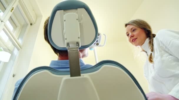Vriendelijke vrouwelijke tandarts in gesprek met de patiënt — Stockvideo