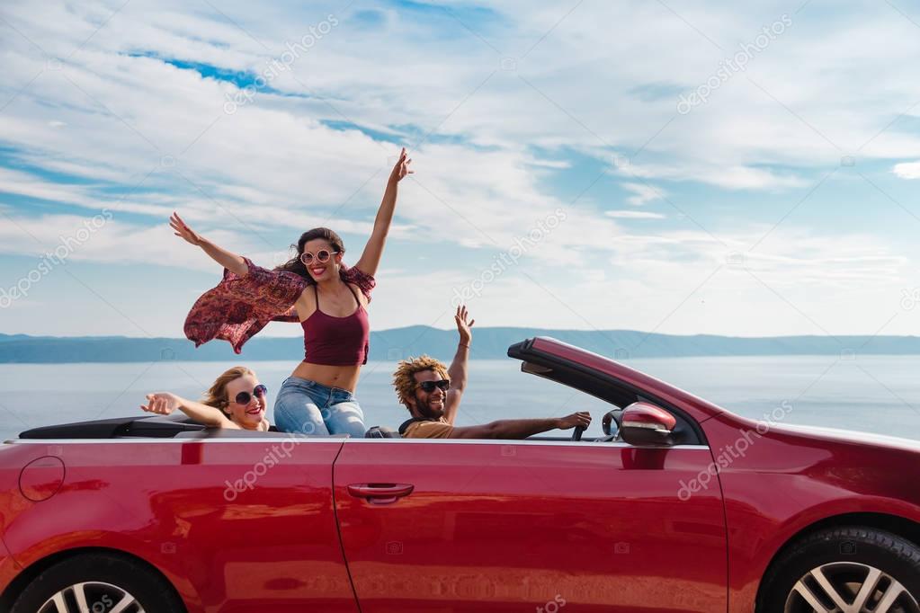 people waving from the convertible