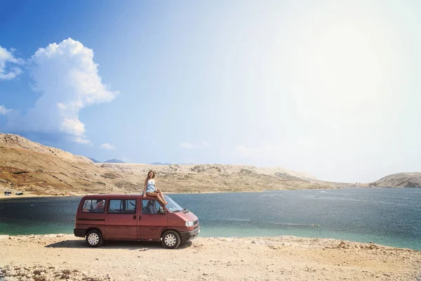 Mooi gelooid meisje op een dak van een rode busje — Stockfoto