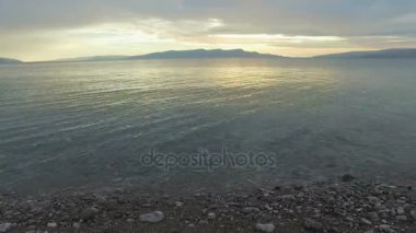 Deniz ve çakıl plaj gün batımında