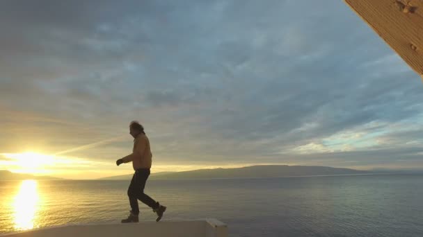 Hombre saltando en la pared en la orilla del mar — Vídeo de stock