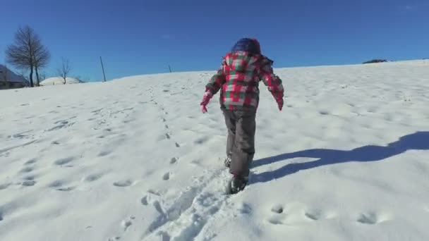 Ребенок поднимается на снежный холм — стоковое видео