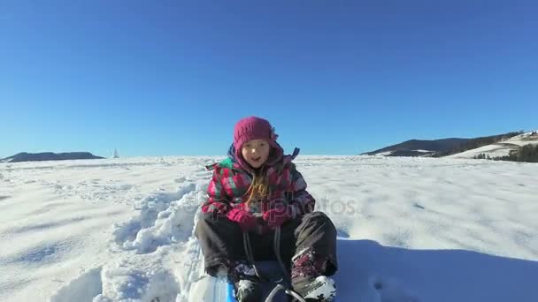 Fille descendant traîneau de colline sur colline enneigée — Video