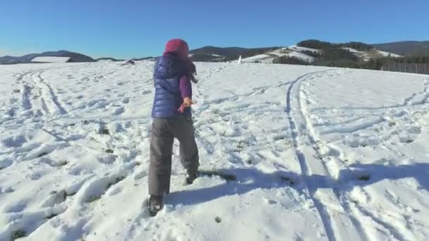 Девушка, идущая по снежному холму — стоковое видео
