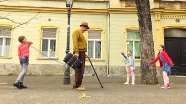 Yaşlı adam sokakta üç kız bir atlama ip atlama.