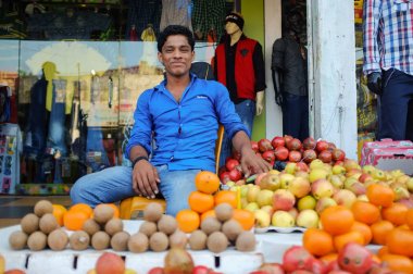 Sokak satıcısı meyve standında oturmuş.