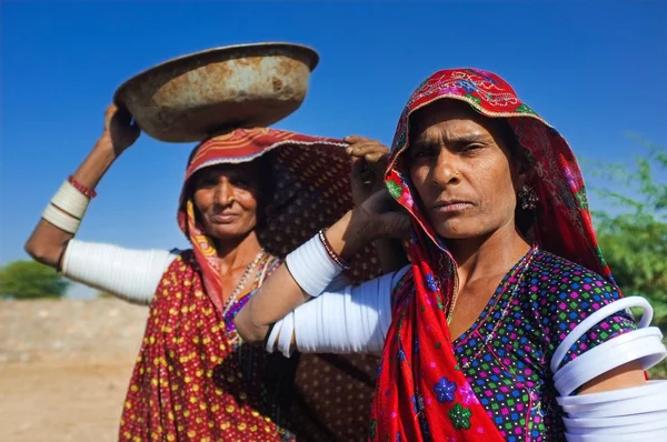 Rabari tribeswomen stojí v poli nosit oděvy a horní rameno náramky. Vyvažuje jeden kýbl na hlavu. Rabari jsou indické komunity v státě Gudžarát. — Stock fotografie