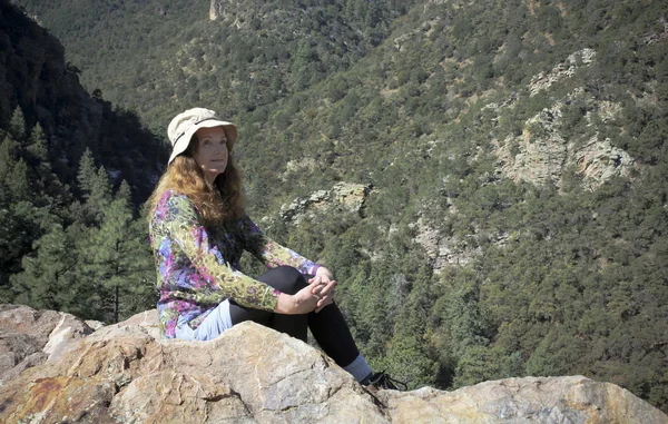 Una mujer en una cornisa con vistas a un bosque —  Fotos de Stock