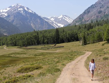 Bir kadın bir yol Alp döngü Backcountry karanlık yol üzerinde yürür.