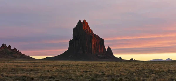 Un paisaje Shiprock contra un cielo rayado al amanecer — Foto de Stock