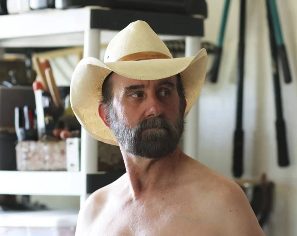 Ein bärtiger Cowboy, der in seinem Geräteschuppen putzt — Stockfoto