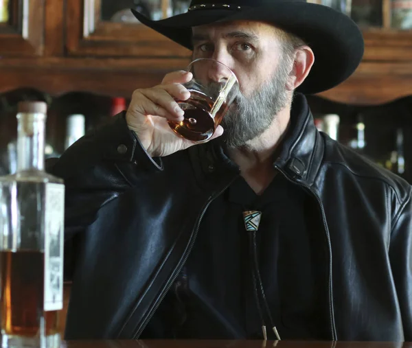 A Bearded Cowboy in Black Drinking Alone in a Saloon — Stock Photo, Image