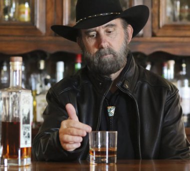 Yalnız bir barda oturan Siyah sakallı bir kovboy