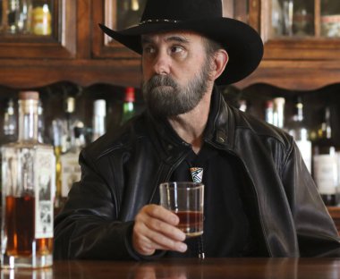 Yalnız bir barda oturan Siyah sakallı bir kovboy