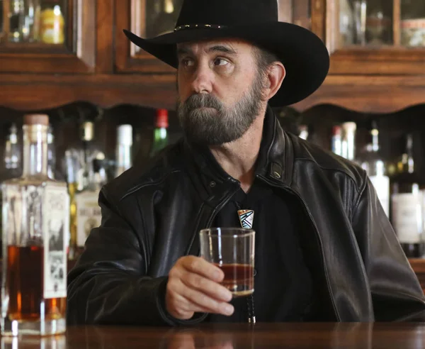Yalnız bir barda oturan Siyah sakallı bir kovboy