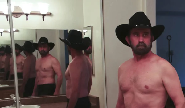 戴着黑色帽子的无上装牛仔在浴室镜子里反射出来 — 图库照片