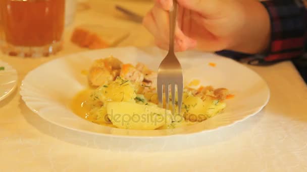 На столе тарелка с картофельным салатным хлебом и соком. Кусок картошки пронзают вилкой. Крупный план — стоковое видео