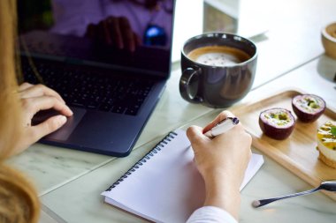 Çalışma ve içme kahve fincanı dizüstü bilgisayar kullanan kadın