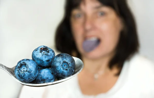 Arándanos jugosos azules en primer plano cuchara. Mujer borrosa de fondo — Foto de Stock