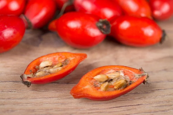 Close-up of halved red rosehip with core on wooden background — Stock Photo, Image