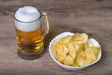 Bira bira ve kızarmış patates cipsi ahşap bir masa üzerinde